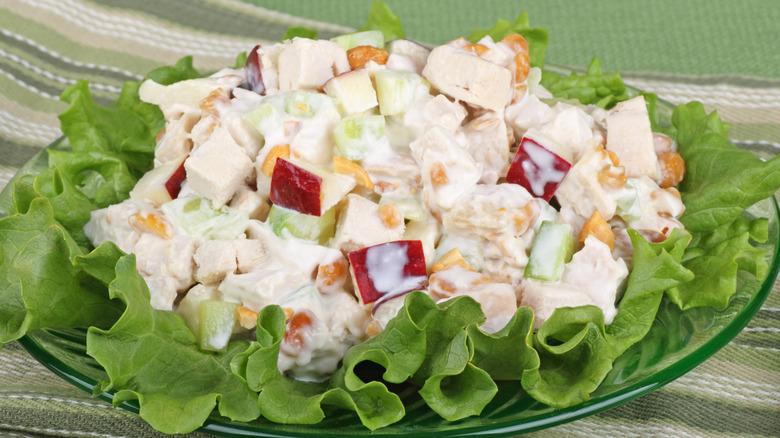 Chicken salad with apples on lettuce on a glass plate