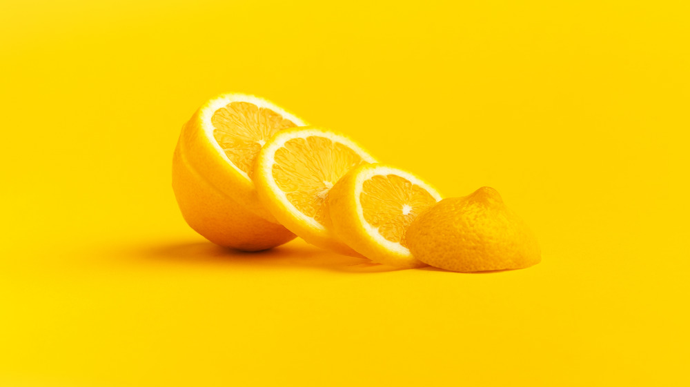 Sliced and halved lemon on yellow background