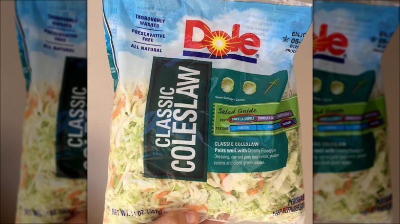 Hand holding bag of Dole classic coleslaw