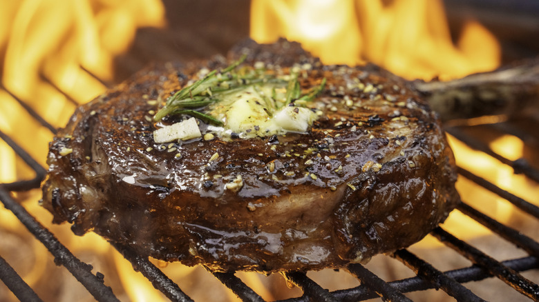 Seasoned ribeye on grill with flames