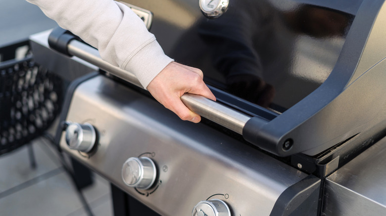 Hand opening a grill lid