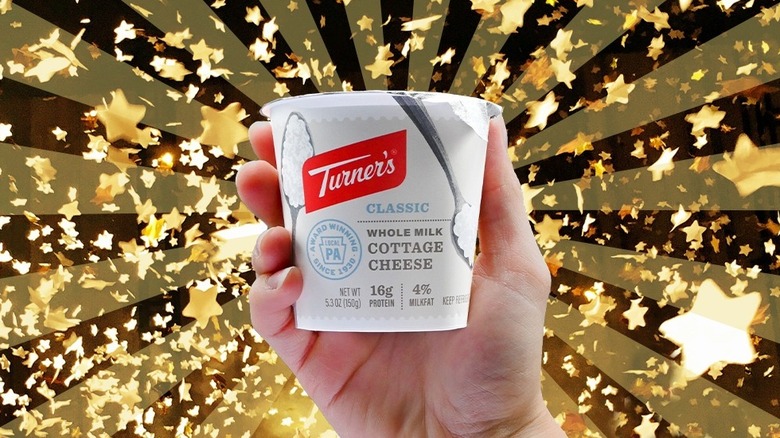 hand holding a container of Turner's cottage cheese with starry background