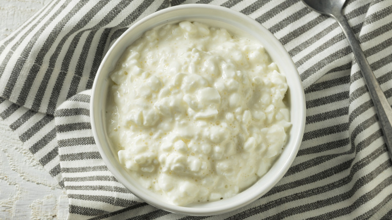 cottage cheese beside a spoon on a striped tablecloth