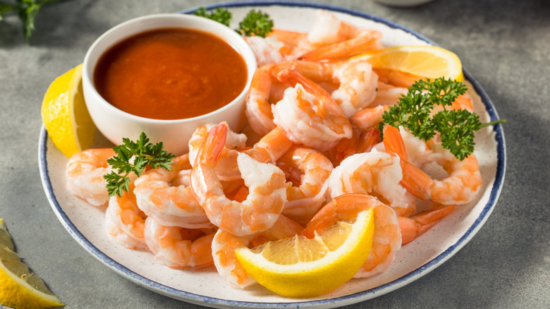 Cooked shrimp on a plate with cocktail sauce