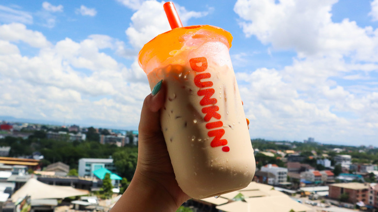 Hand raising a cup of Dunkin' iced coffee