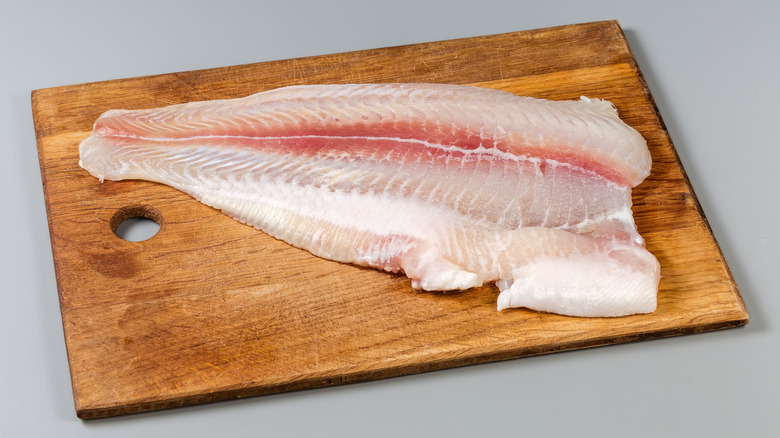 A fillet cut of pangasius fish on a wood cutting board