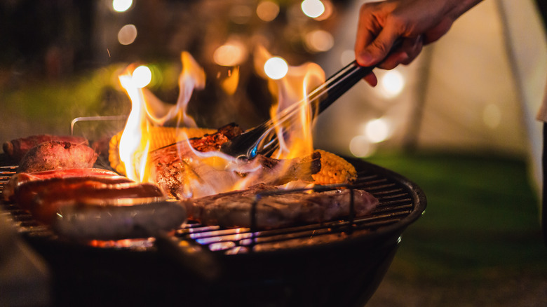 Tongs flipping items on grill