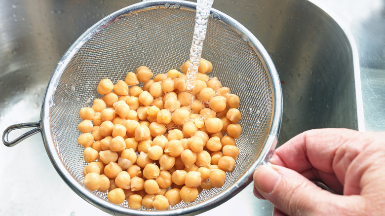 Rinsing canned beans in the sink with a mesh sieve