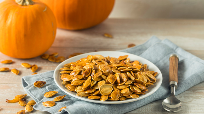 Pumpkin seeds next to pumpkins