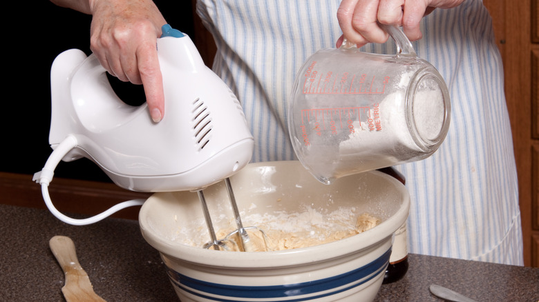 Person adding flour to batter