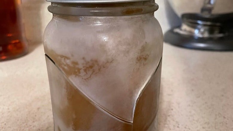 Frozen chicken stock in a cracked glass jar.