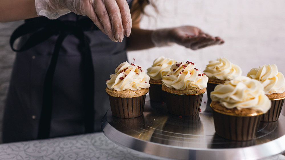 Baker frosting vanilla cupcakes