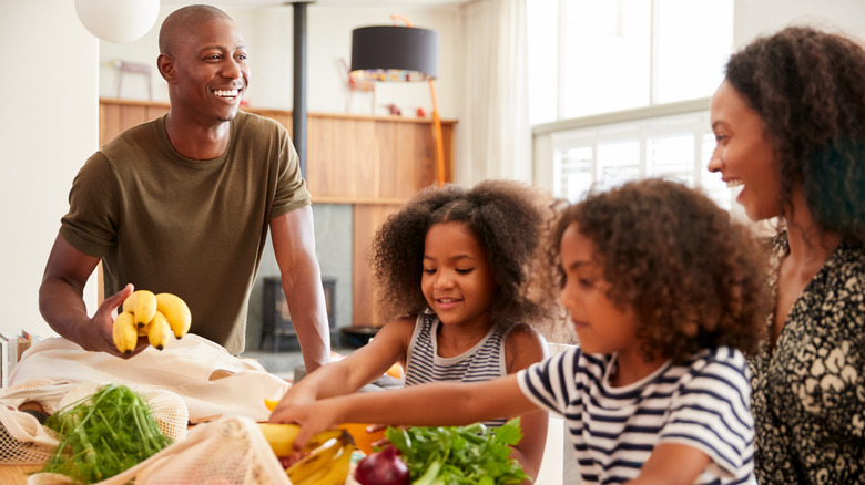 Family happily opens bags of fruit and vegetables