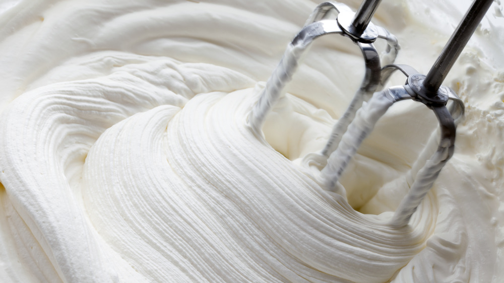 Whipped cream in a bowl with beaters