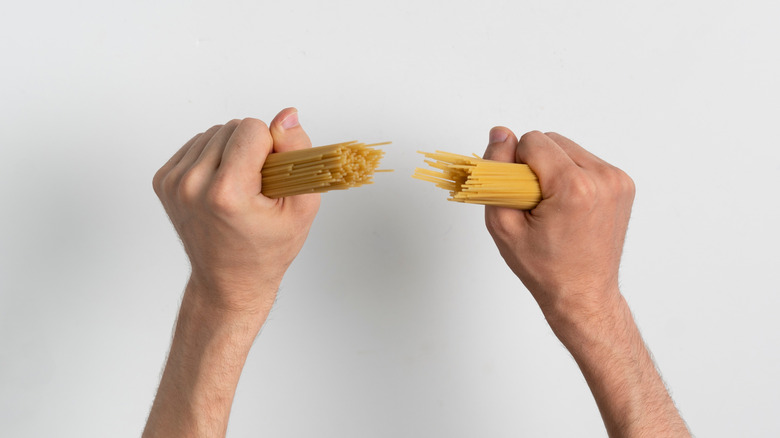 hands breaking spaghetti noodles in half