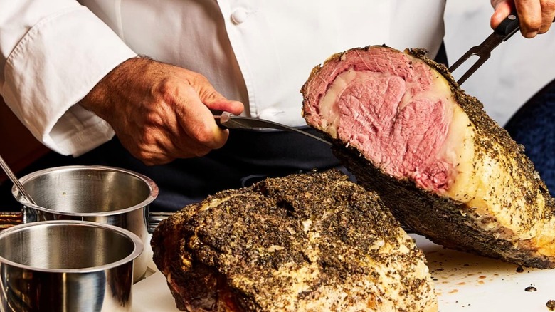Chef displaying the inside of an herb-pressed prime rib served at Palladino's Steak and Seafood