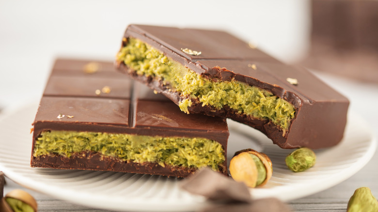 Dubai style chocolate broken in half on a plate, showing the pistachio and kadayif center