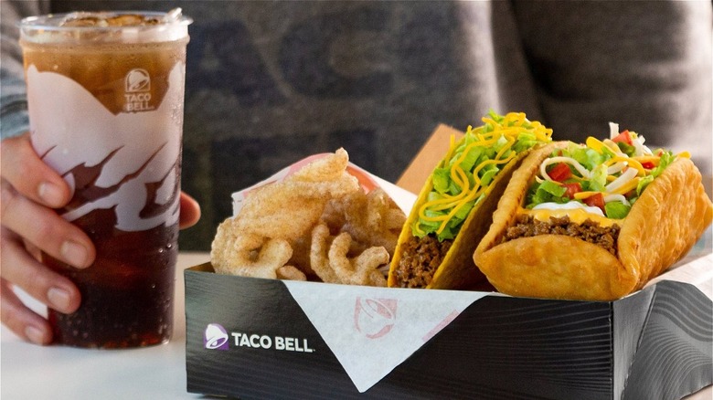 A Taco Bell meal with tacos, sides, and a soda