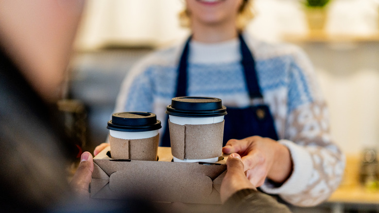Barista serving coffee in to-go cups