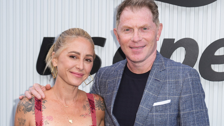 Celebrity chef couple Brooke Williamson and Bobby Flay smiling at event.