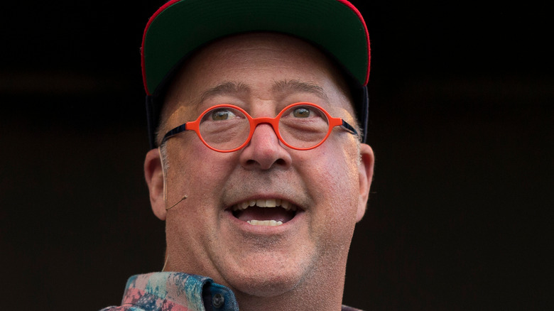 Close up of Andrew Zimmern wearing glasses and hat