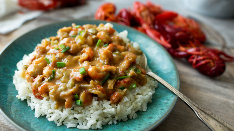Crawfish etouffee on plate next to crawfish shells