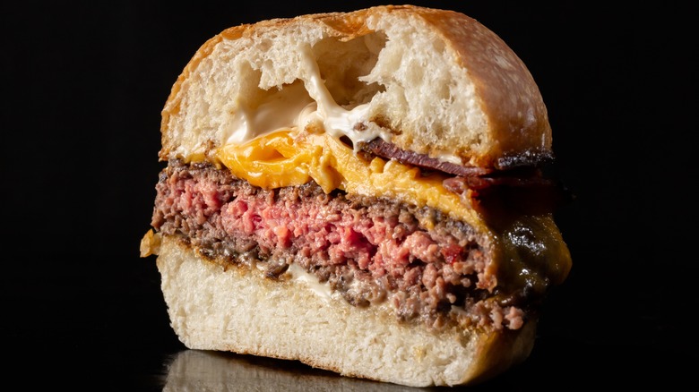 rare hamburger on bun with cheese