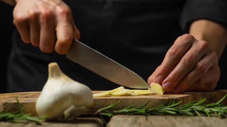 chef cutting garlic with knife