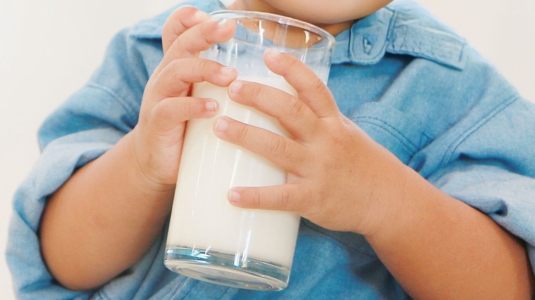 Toddler holding glass of milk