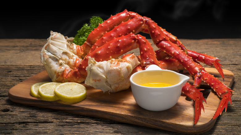 cooked king crab legs on cutting board with butter and lemon
