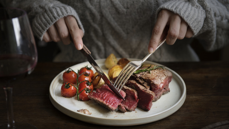 woman cutting rare steak