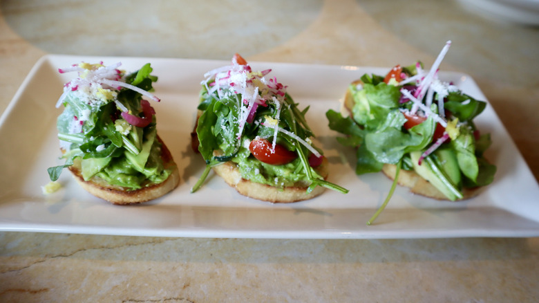 Three pieces of avocado toast on white plate