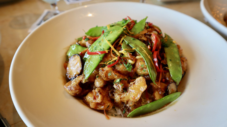 Orange cauliflower bowl topped with snow peas