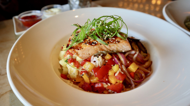 Salmon in white bowl atop vegetables