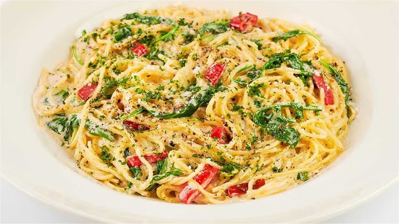 Plate of pasta with greens and red peppers