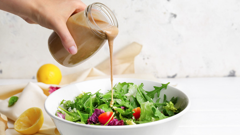 Pouring homemade dressing onto a salad