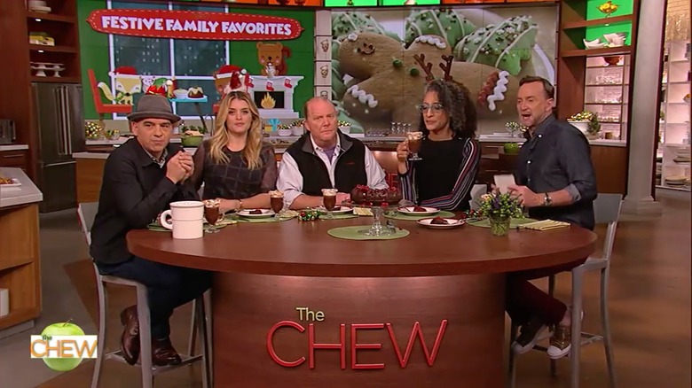 Michael Symon, Daphne Oz, Mario Batali, Carla Hall, and Clinton Kelly, sitting around a table on the set of 