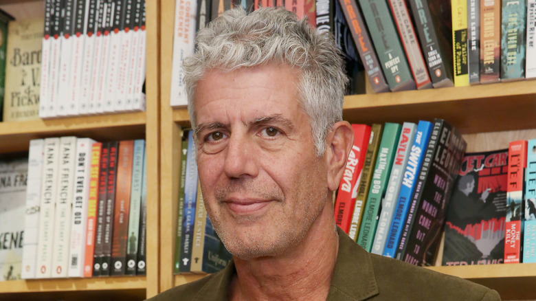 Anthony Bourdain in green blazer with books