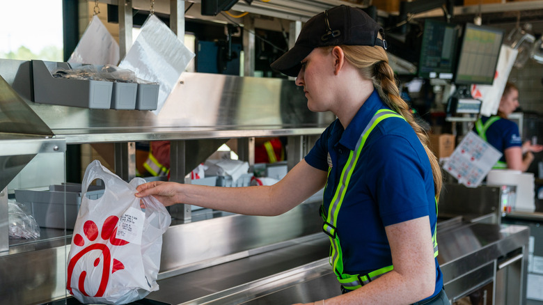 A Chick-fil-A employee grabbing a to-go bag inside the restaurant.