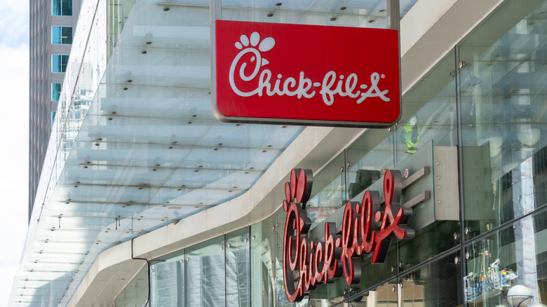 Chick-fil-A signage outside of larger office-type building during daytime.