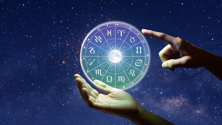 Hands holding zodiac wheel