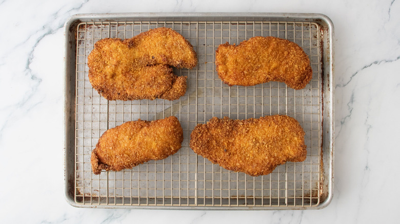 Fried chicken cutlets draining on wire rack