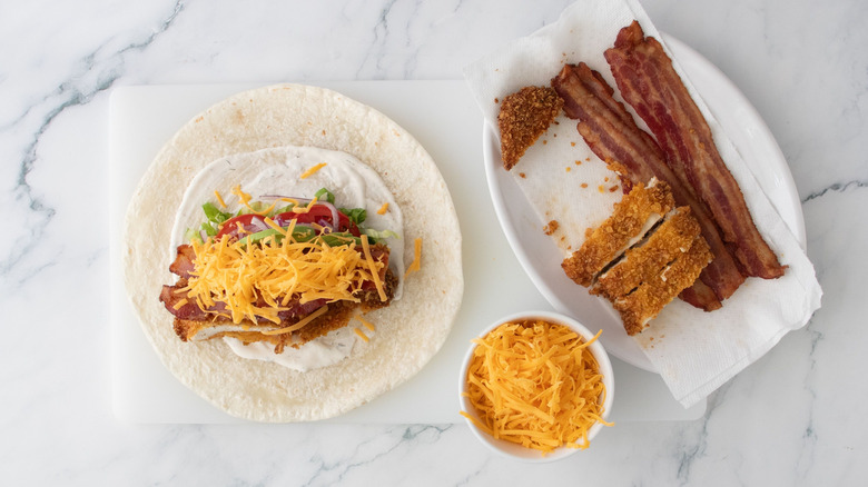 Chicken bacon ranch wrap next to bowl of cheese and chicken and bacon on plate