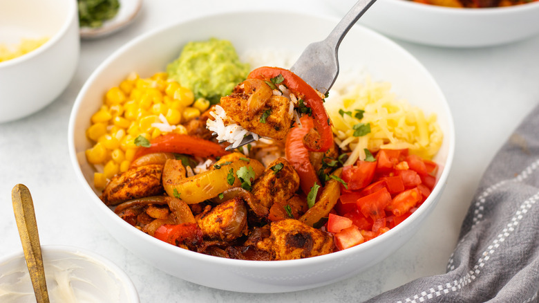 Loaded chicken fajita rice bowl with forkful taken out