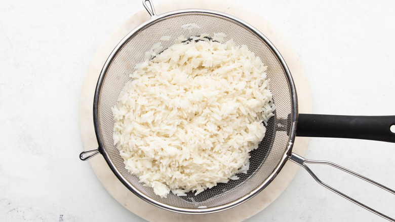 Cooked basmati rice in strainer over saucepan