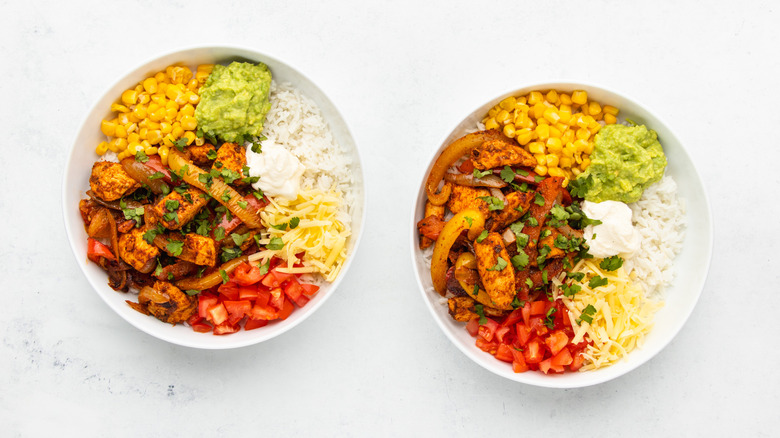 Two chicken fajita rice bowls with various Mexican-inspired toppings