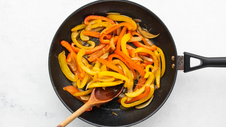 Sliced peppers and onions sauteing in frying pan