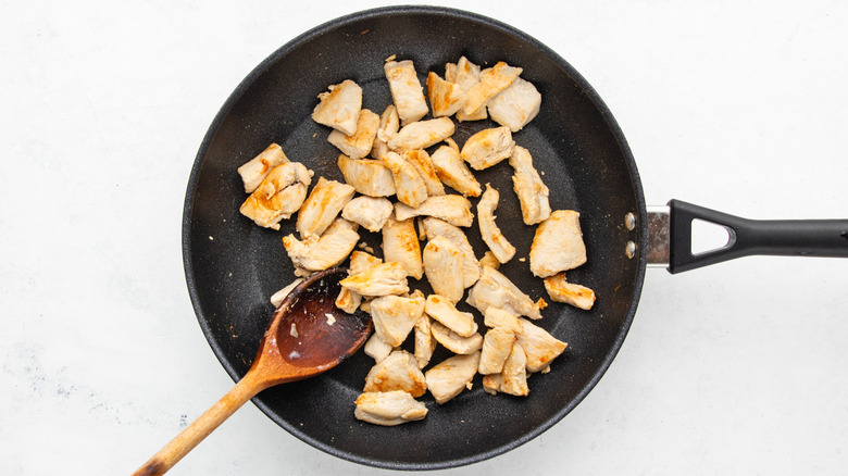 Diced chicken breast cooking in frying pan