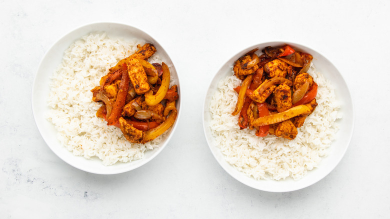 Two bowls of white rice topped with chicken fajita mixture