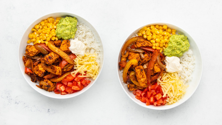 Two chicken fajita rice bowls with various Mexican-inspired toppings
